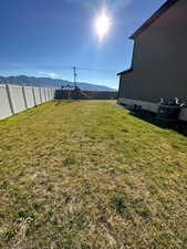 View of yard with central AC unit, a mountain view, and a fenced backyard