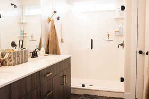 Full bathroom featuring a sink, double vanity, and a shower stall