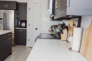 Kitchen featuring decorative backsplash, light wood finished floors, high quality fridge, and light countertops