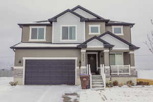 Craftsman-style home with driveway, a porch, an attached garage, stucco siding, and stone siding
