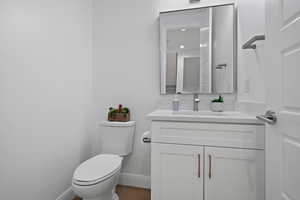 Bathroom featuring baseboards, toilet, and vanity