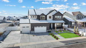 View of front of home with a residential view, board and batten siding, concrete driveway, and fence