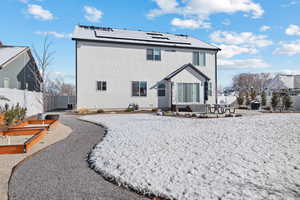 Back of property featuring fence, solar panels, a vegetable garden, stucco siding, and a patio area