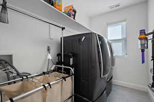 Clothes washing area with laundry area, washer and dryer, baseboards, and visible vents