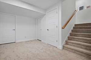 Basement featuring baseboards, carpet floors, and stairs