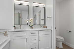 Bathroom with double vanity, toilet, a garden tub, and a sink