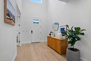 Entryway with light wood-style flooring, a high ceiling, and baseboards