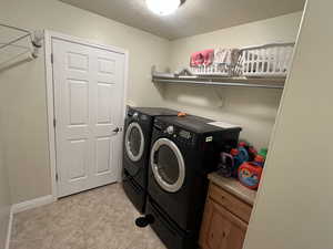 Washroom featuring a textured ceiling, independent washer and dryer, and laundry area