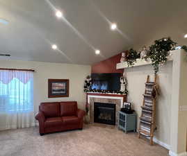 Living room featuring visible vents, recessed lighting, a fireplace, vaulted ceiling, and carpet flooring