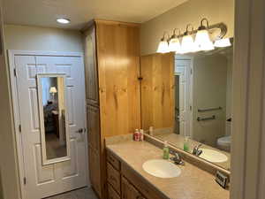 Bathroom with toilet, a textured ceiling, and vanity