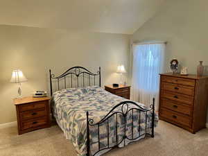 Bedroom featuring lofted ceiling and light colored carpet