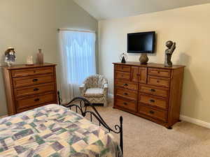 Carpeted bedroom with lofted ceiling and baseboards