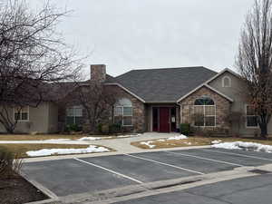 Single story home featuring stone siding, stucco siding, roof with shingles, and uncovered parking
