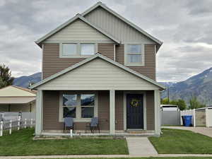 View of front of house featuring a porch and a mountain view, yard and fence