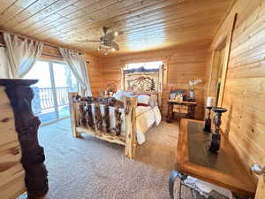 Carpeted bedroom with wood ceiling, access to outside, and wood walls