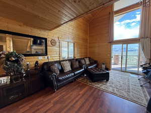 Living area with wooden ceiling, wood walls, high vaulted ceiling, and wood finished floors