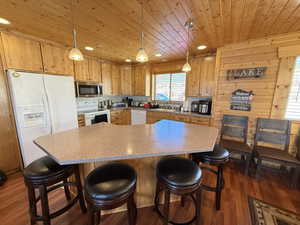 Kitchen with white appliances, wood ceiling, dark wood-type flooring, light countertops, and recessed lighting