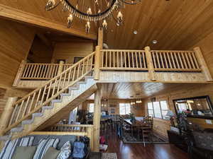 Living area with a high ceiling, a chandelier, wooden walls, wooden ceiling, and stairway