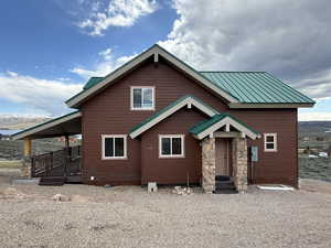 Rustic home featuring metal roof, stone siding, and a standing seam roof
