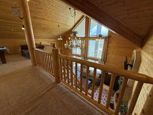 Hallway with wood ceiling, wood walls, carpet floors, a chandelier, and vaulted ceiling
