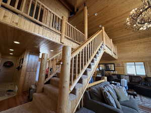 Stairs with wooden ceiling, wood finished floors, wood walls, a chandelier, and a towering ceiling