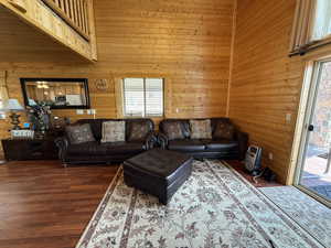Living room featuring healthy amount of natural light, wood walls, wood finished floors, and a high ceiling