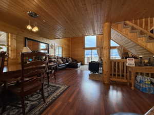 Living area featuring wood walls, wooden ceiling, wood finished floors, stairs, and a wood stove
