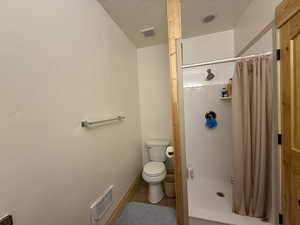 Bathroom with a shower stall, toilet, tile patterned floors, and baseboards