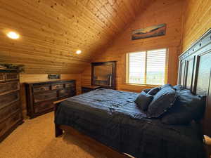 Bedroom featuring vaulted ceiling, wood walls, light colored carpet, and recessed lighting