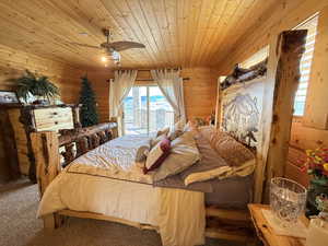 Bedroom featuring wood ceiling, carpet flooring, wood walls, and access to exterior