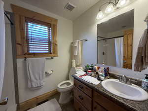 Full bathroom featuring a textured ceiling, a shower with shower curtain, baseboards, tile patterned floors, and toilet