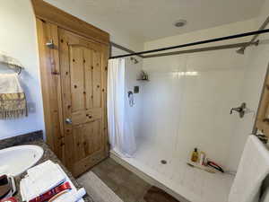 Full bath featuring a stall shower, a textured ceiling, a sink, and tile patterned flooring