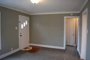 Foyer with crown molding and baseboards