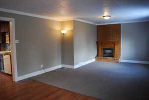 Unfurnished living room featuring a sink, baseboards, ornamental molding, and a fireplace