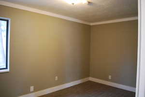 Spare room with baseboards, dark carpet, and a textured ceiling