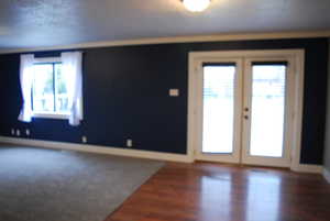 Unfurnished room featuring french doors, baseboards, and wood finished floors