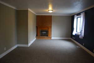 Unfurnished living room with visible vents, baseboards, ornamental molding, carpet floors, and a fireplace