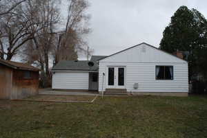 Rear view of property with board and batten siding, entry steps, french doors, a yard, and a patio area