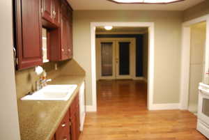 Kitchen featuring light wood finished floors, range, baseboards, and a sink