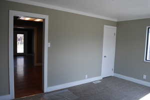 Unfurnished room with visible vents, carpet flooring, baseboards, and ornamental molding