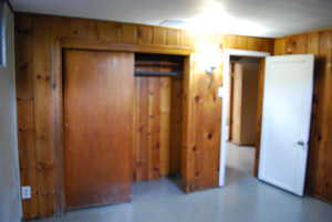 Unfurnished bedroom with finished concrete flooring and wood walls