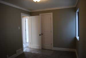 Spare room with visible vents, a textured ceiling, crown molding, and baseboards