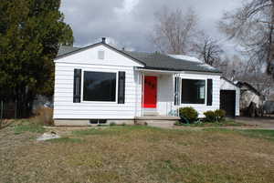 Bungalow-style home featuring a front lawn, a garage, and a shingled roof