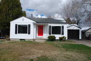 View of front of property featuring a garage, concrete driveway, a front yard, and a shingled roof