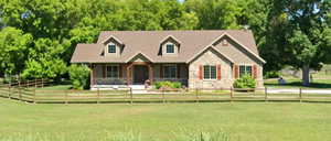 New england style home with a front lawn, stone siding, and a fenced front yard