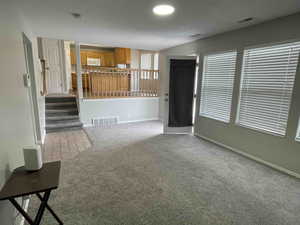 Unfurnished living room with visible vents, baseboards, and carpet