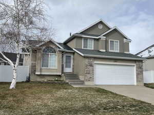 View of front of property featuring stucco siding, entry steps, a garage, and fence