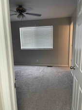 Carpeted empty room with baseboards and a ceiling fan