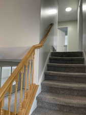 Stairs featuring a textured ceiling and carpet