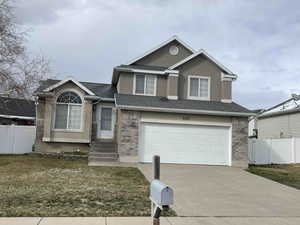 View of front of property with entry steps, an attached garage, fence, and brick work